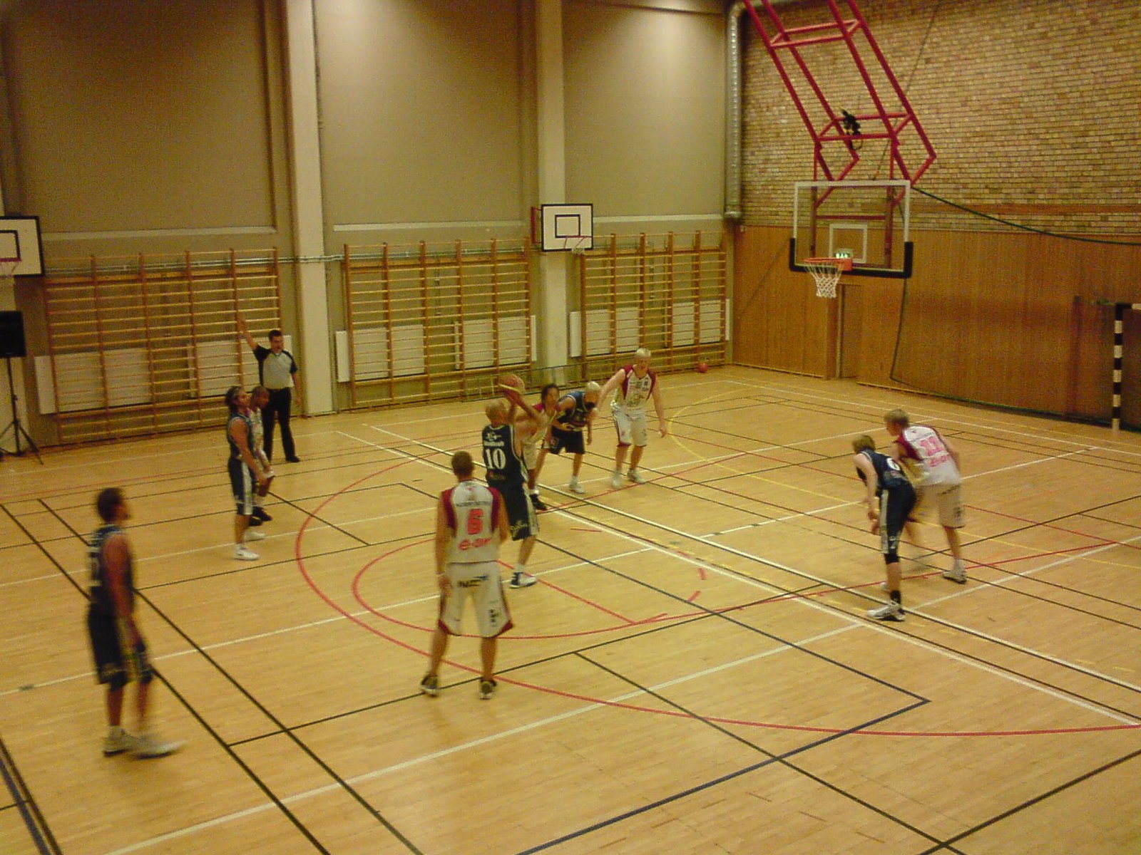 Basketspelare vid straffkastlinjen i en idrottshall med träpanel och basketkorg